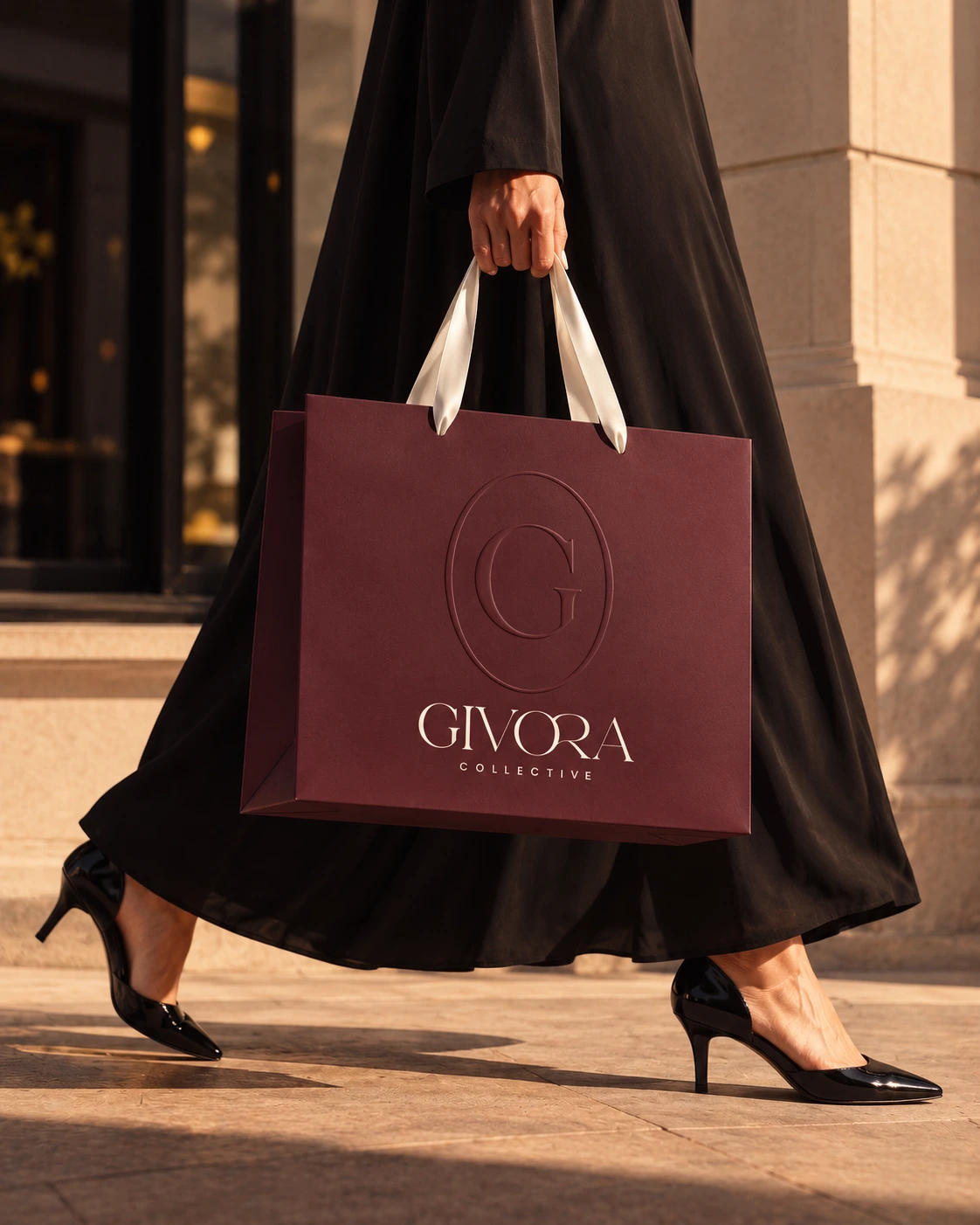 A Burgundy Givora bag carried beside a stone building
